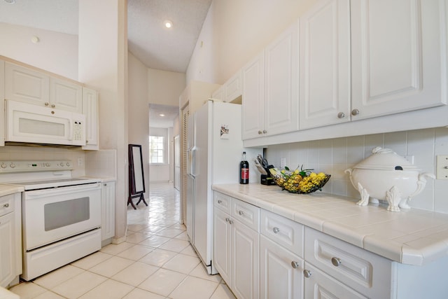 kitchen featuring tile countertops, white cabinetry, white appliances, and light tile patterned floors