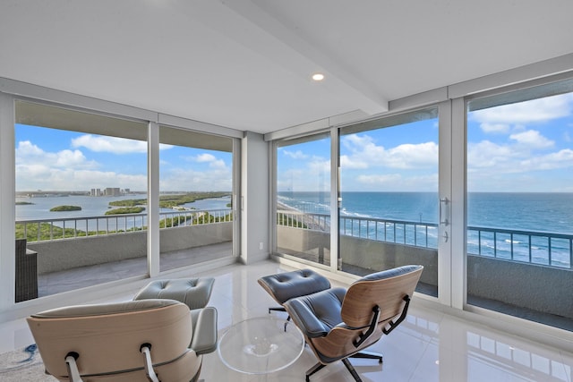 sunroom with plenty of natural light, beam ceiling, and a water view