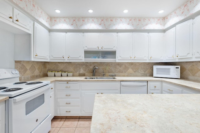 kitchen featuring white appliances, backsplash, sink, light tile patterned floors, and white cabinetry