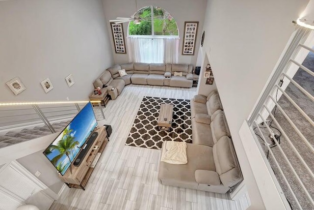 living room with ceiling fan, wood-type flooring, and a high ceiling