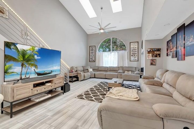 living room featuring hardwood / wood-style floors, ceiling fan, high vaulted ceiling, and a skylight