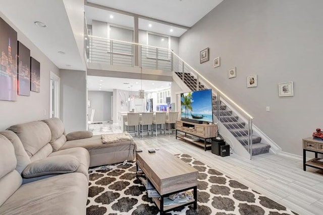 living room with light hardwood / wood-style flooring and a towering ceiling