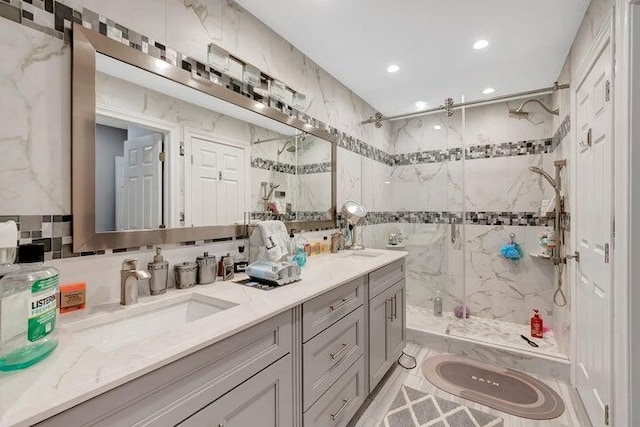 bathroom with a tile shower, vanity, and tile walls