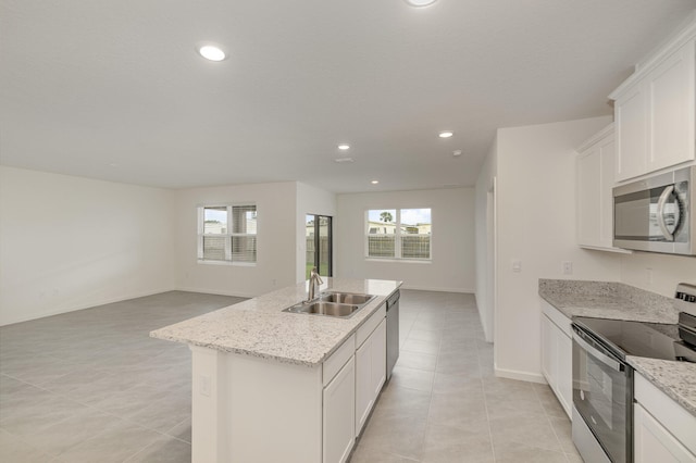 kitchen featuring light stone countertops, a center island with sink, white cabinets, and appliances with stainless steel finishes