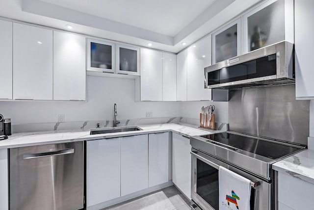 kitchen with white cabinetry, light stone countertops, sink, and stainless steel appliances