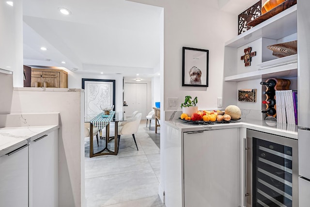 kitchen featuring white cabinets, light stone countertops, and wine cooler