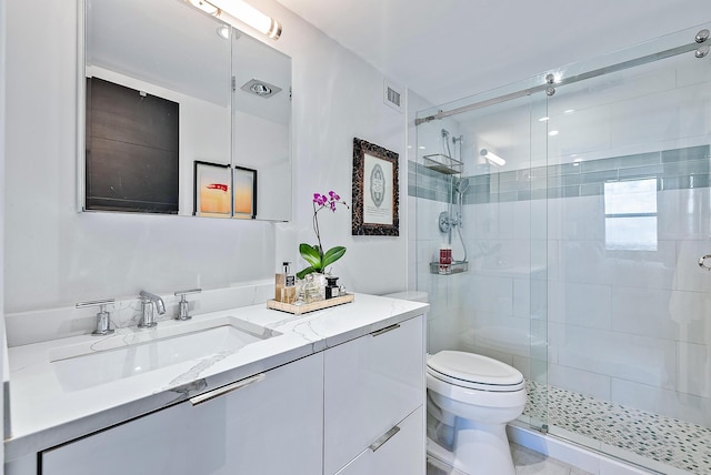 bathroom featuring vanity, toilet, and a shower with door