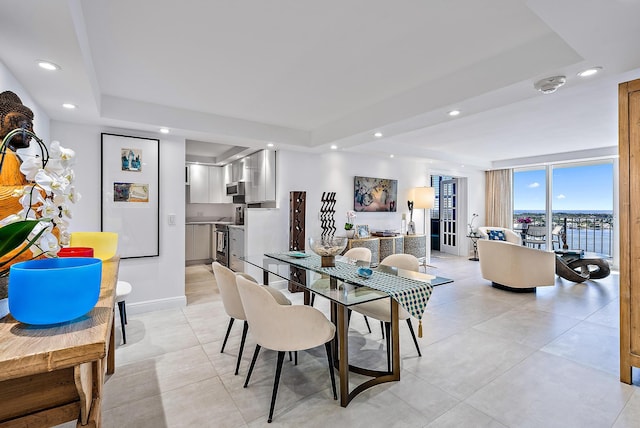 dining space featuring a tray ceiling and a wall of windows