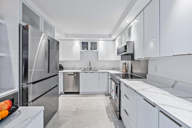 kitchen with light stone countertops, white cabinetry, sink, and appliances with stainless steel finishes