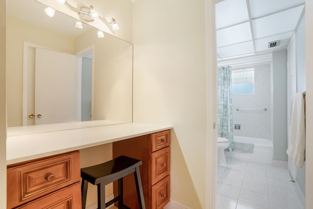 full bathroom with a drop ceiling, vanity, tile patterned flooring, tiled shower / bath combo, and toilet