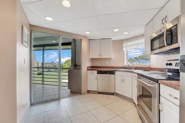 kitchen with white cabinets, light tile patterned floors, sink, and appliances with stainless steel finishes