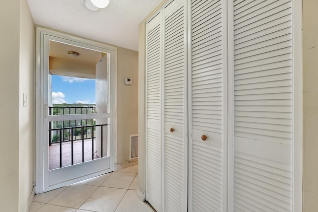 hall featuring light tile patterned floors and a textured ceiling