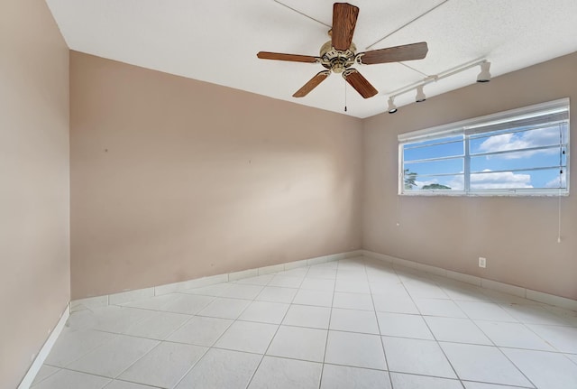 tiled empty room featuring ceiling fan, track lighting, and a textured ceiling