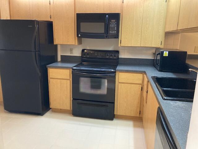 kitchen featuring light brown cabinets, sink, backsplash, and black appliances