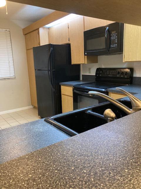 kitchen featuring light brown cabinets, light tile patterned floors, and black appliances