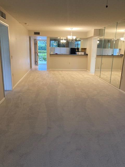 unfurnished living room featuring carpet and a chandelier