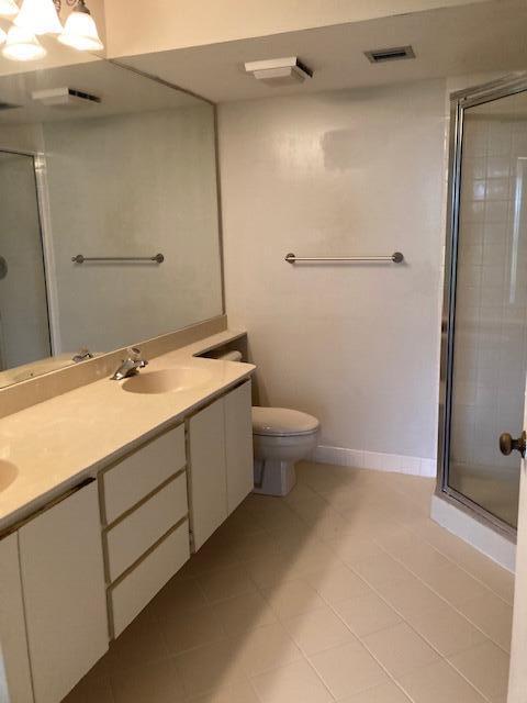 bathroom with tile patterned flooring, vanity, toilet, and walk in shower