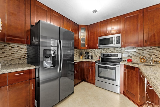 kitchen featuring light stone countertops, sink, appliances with stainless steel finishes, and tasteful backsplash