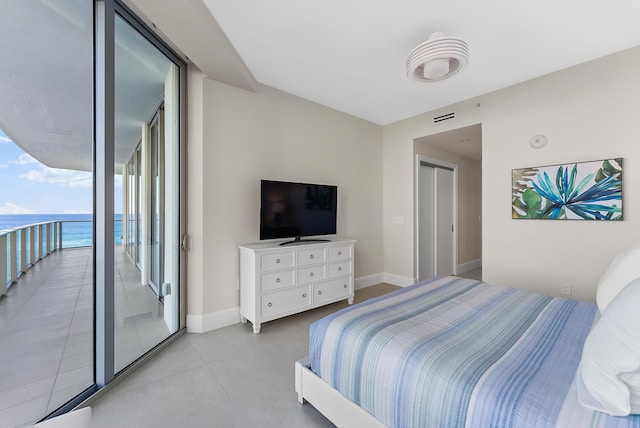 bedroom featuring expansive windows, access to outside, and a water view