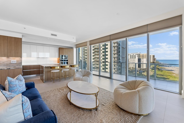 tiled living room featuring a water view, a wall of windows, and sink