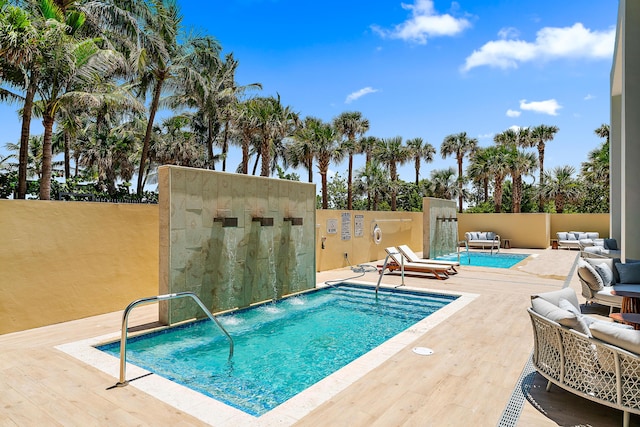 view of pool featuring outdoor lounge area, pool water feature, and a patio