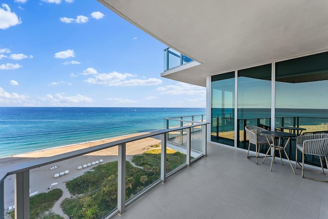 balcony with a water view and a view of the beach