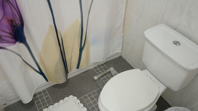 bathroom featuring tile patterned floors, a shower with curtain, toilet, and tile walls