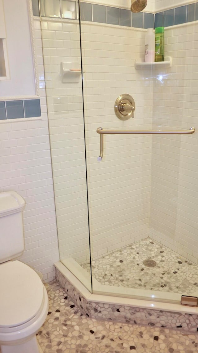 bathroom with a tile shower, tile walls, and toilet