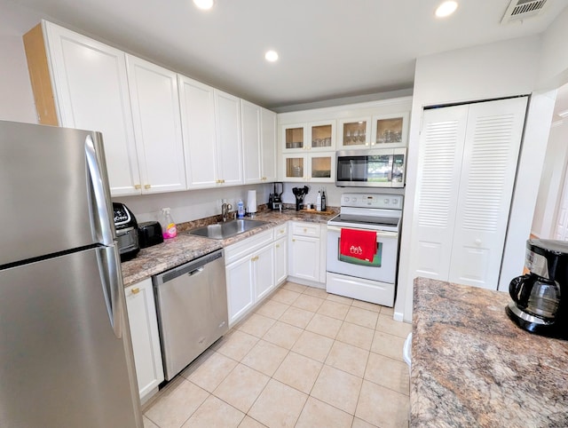 kitchen featuring sink, light tile patterned floors, appliances with stainless steel finishes, light stone counters, and white cabinetry