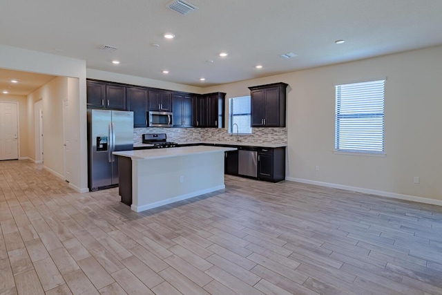 kitchen with tasteful backsplash, visible vents, appliances with stainless steel finishes, a center island, and light countertops