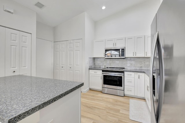 kitchen featuring white cabinets, appliances with stainless steel finishes, tasteful backsplash, and light hardwood / wood-style flooring