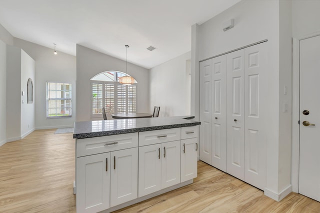 kitchen featuring white cabinets, light hardwood / wood-style flooring, hanging light fixtures, and a kitchen island