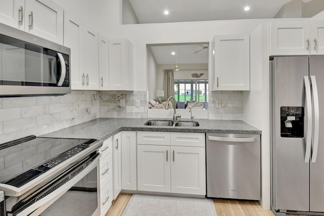 kitchen with sink, stainless steel appliances, light hardwood / wood-style flooring, decorative backsplash, and white cabinets