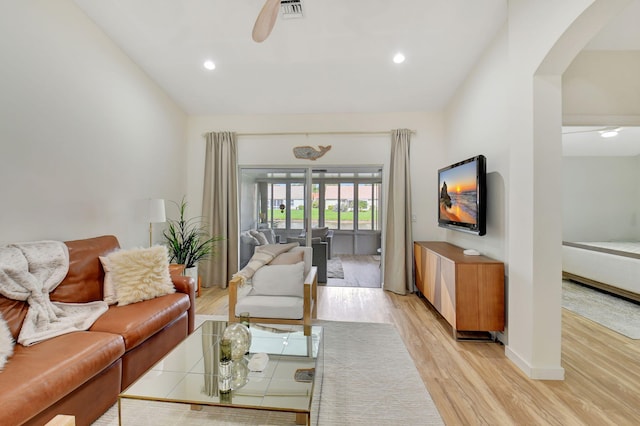 living room with ceiling fan, light hardwood / wood-style floors, and vaulted ceiling