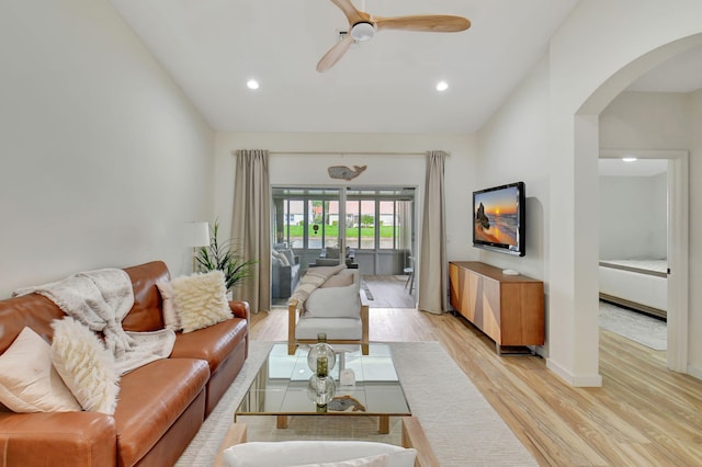 living room with light wood-type flooring, vaulted ceiling, and ceiling fan