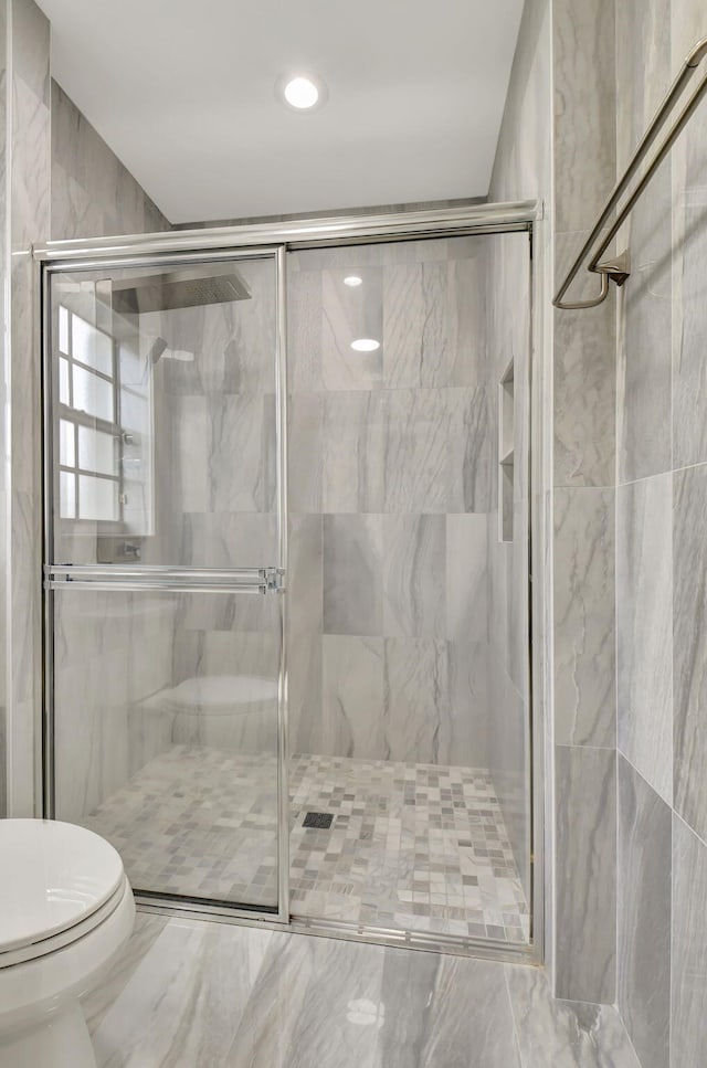 bathroom featuring toilet and a shower with door