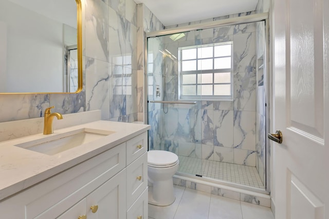 bathroom with vanity, a shower with door, tile walls, tile patterned flooring, and toilet