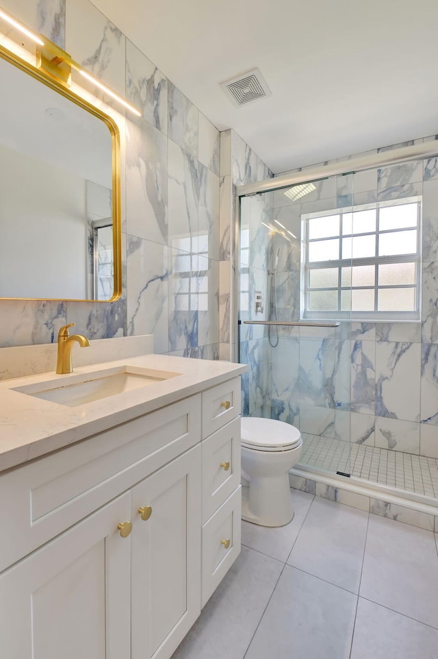 bathroom featuring tile patterned flooring, an enclosed shower, toilet, vanity, and tile walls