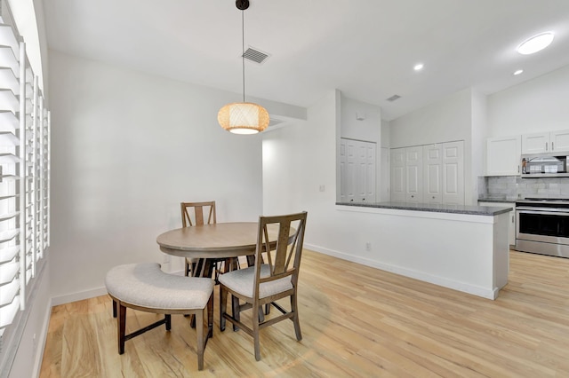 dining area featuring vaulted ceiling and light wood-type flooring