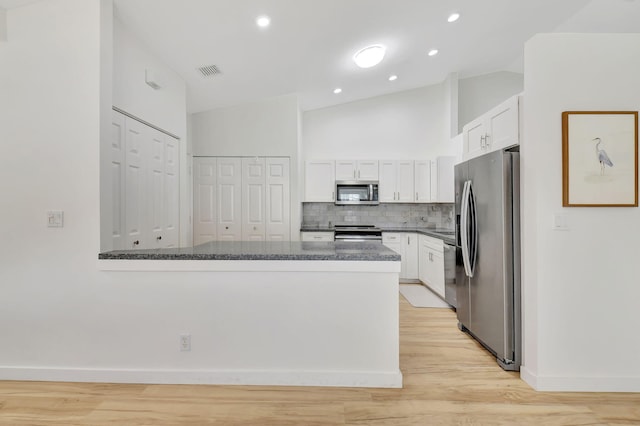 kitchen featuring decorative backsplash, appliances with stainless steel finishes, light hardwood / wood-style flooring, white cabinets, and lofted ceiling