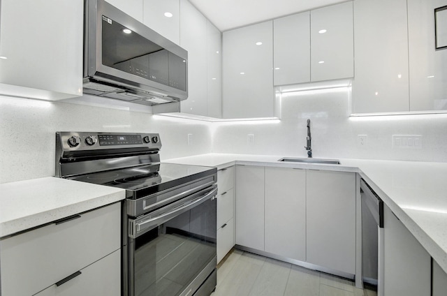 kitchen with sink, white cabinetry, stainless steel appliances, and tasteful backsplash