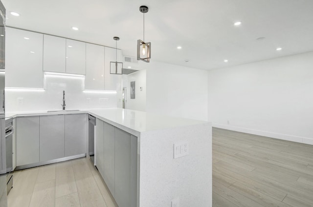 kitchen with sink, decorative light fixtures, light hardwood / wood-style flooring, dishwasher, and white cabinetry