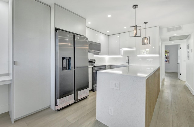 kitchen with white cabinets, sink, light wood-type flooring, appliances with stainless steel finishes, and decorative light fixtures