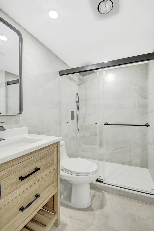 bathroom featuring vanity, a shower with shower door, tile walls, and toilet