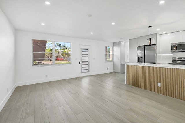 kitchen with pendant lighting, plenty of natural light, white cabinetry, and stainless steel appliances