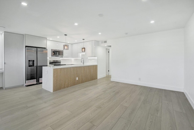 kitchen with white cabinetry, sink, pendant lighting, light hardwood / wood-style floors, and appliances with stainless steel finishes