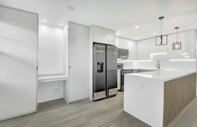 kitchen featuring stainless steel appliances, sink, white cabinets, light hardwood / wood-style floors, and hanging light fixtures