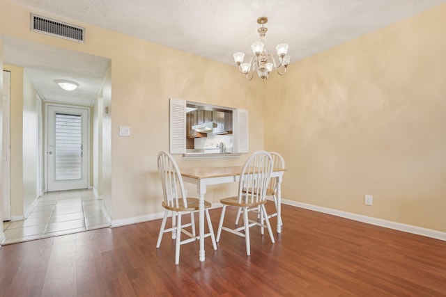 dining space featuring a textured ceiling, an inviting chandelier, and hardwood / wood-style flooring