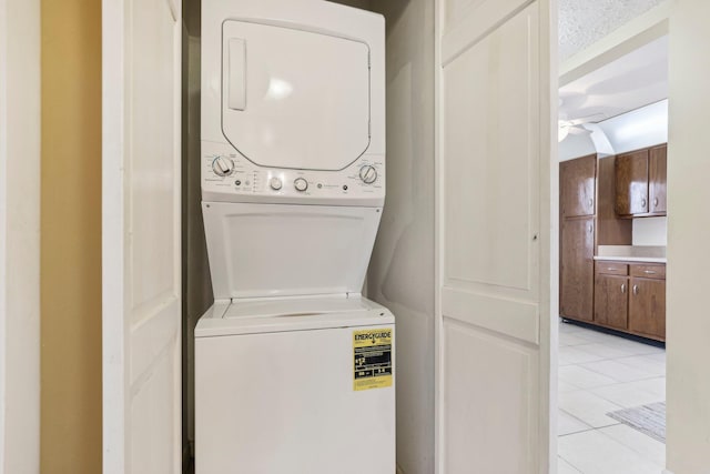 laundry room featuring ceiling fan, stacked washing maching and dryer, and light tile patterned floors