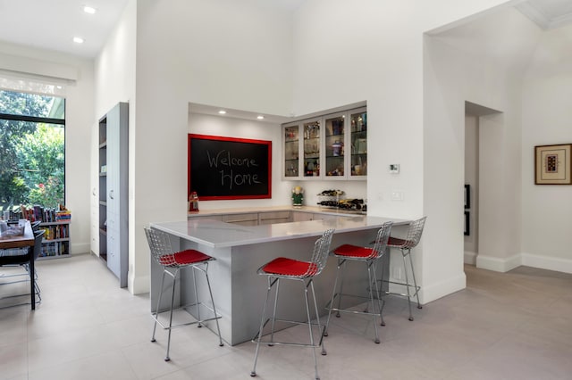 kitchen featuring a breakfast bar area, a high ceiling, and kitchen peninsula